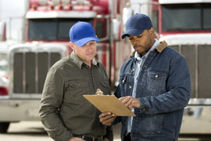 DOT inspector and flatbed driver looking at clipboard during inspection